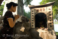Rezando en la puerta de entrada al Templo de Ngoc Son (montaña de Jade) en el lago Hoan Kiem. Barrio Antiguo de Hanoi.